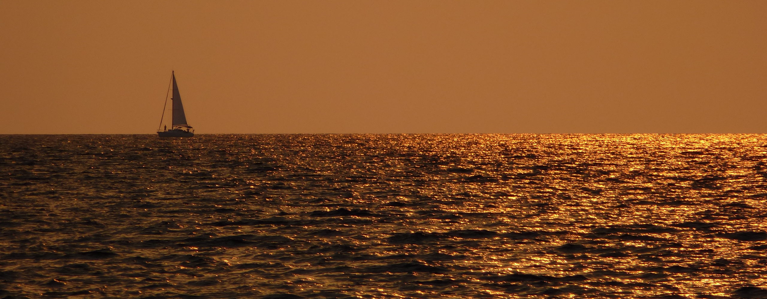 Saltyboys sailing yacht at sunset golden sea